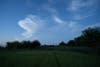 A night sky with a field in the foreground with trails from lightning bugs