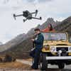 People flying a DJI drone near a jeep